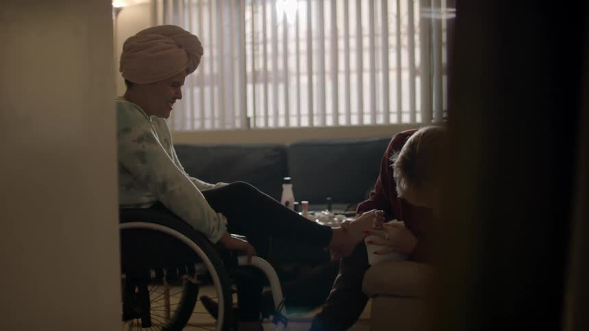 A woman is putting nail polish on someone in a wheelchair