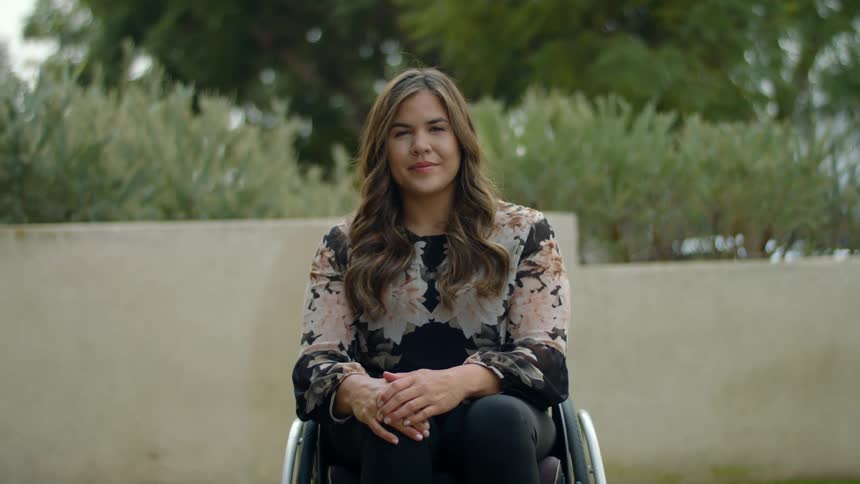 A woman is sitting in a wheelchair outside in spring