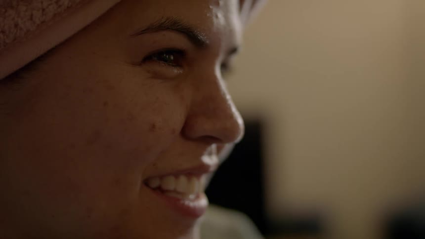 A woman is sitting indoors and smiling
