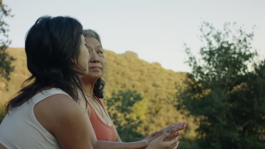 Daughter massages her mother hand while sitting outdoor at morning