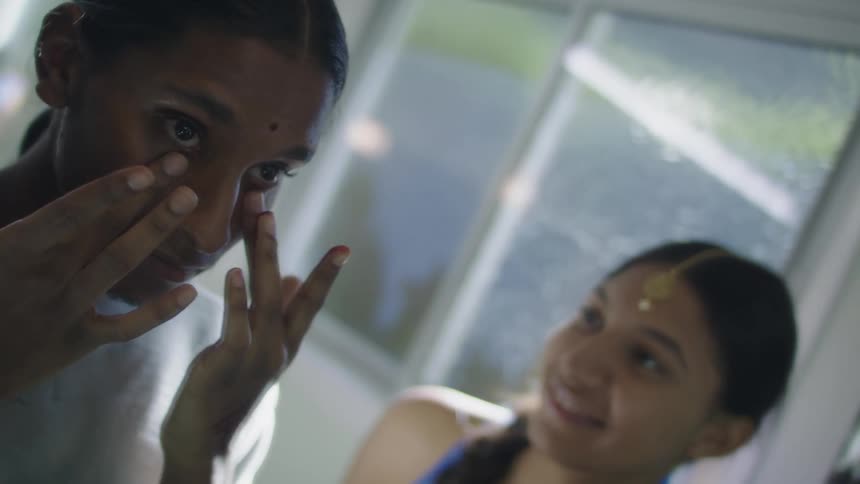 Two girls are putting on makeup indoors during the day