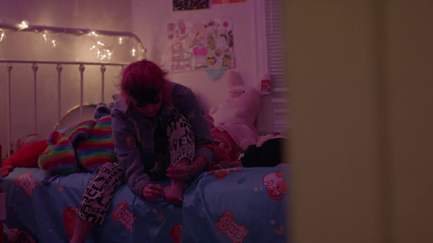 A teenager is painting her nails in her bedroom