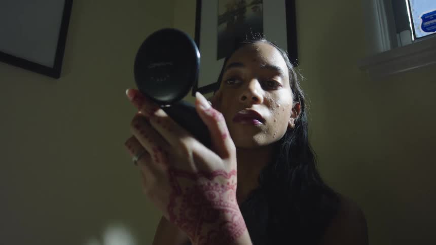 A woman is holding a compact mirror and applying makeup