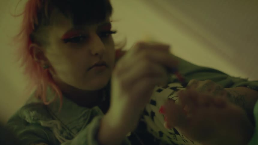 A woman is sitting in a room and applying nail polish