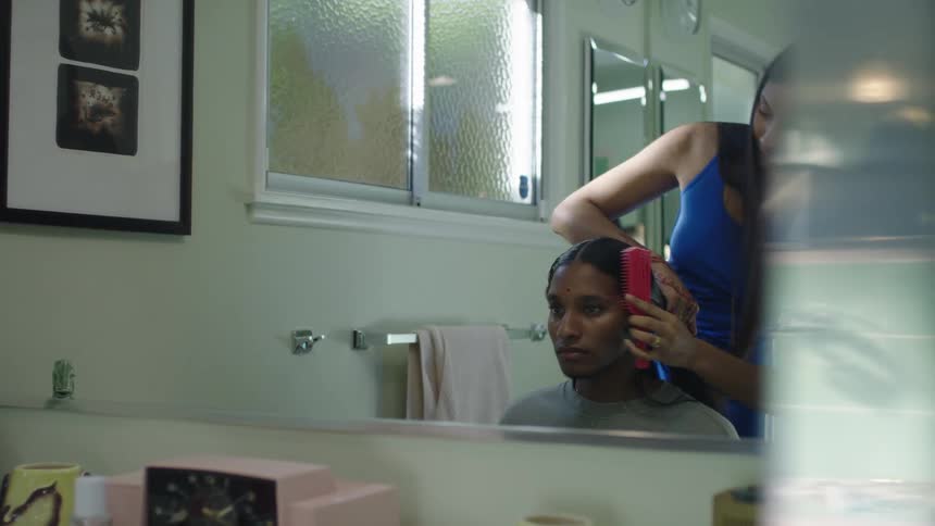 Two women are in a bathroom and styling hair