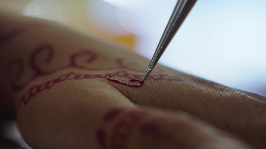 Person applies henna art with applicator