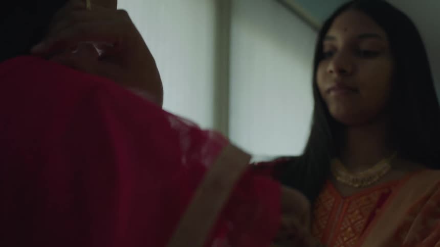 A woman is helping another woman with a sari