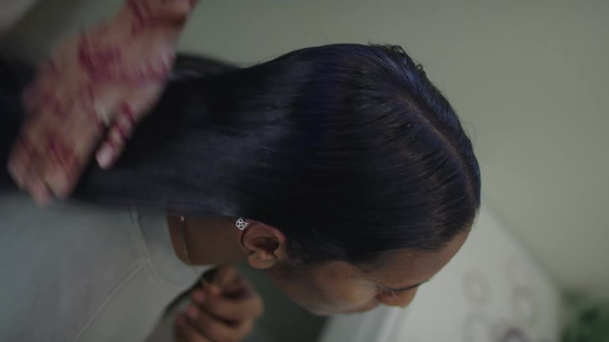 A woman brushes her teenage daughters hair