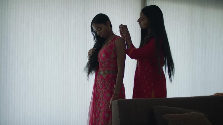Two women are standing in a room and wearing dresses