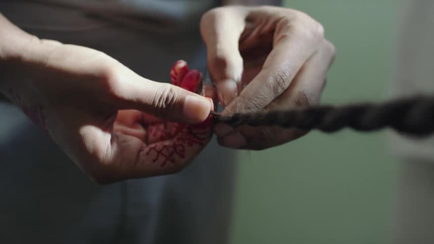 A woman braids another persons hair