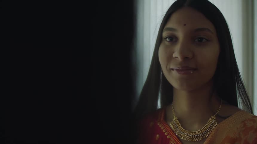 A woman is smiling and standing in a room indoors