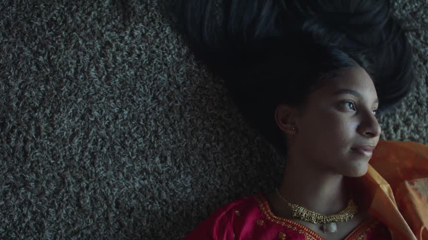 A woman is laying on a carpet on the ground