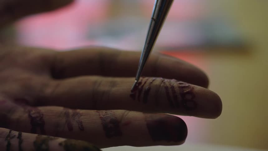 Someone is having designs painted on their fingers with henna paint