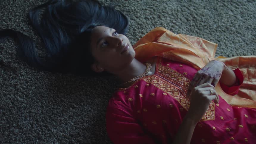 Young indian woman relaxing over a rug in the floor wearing a traditional red saree