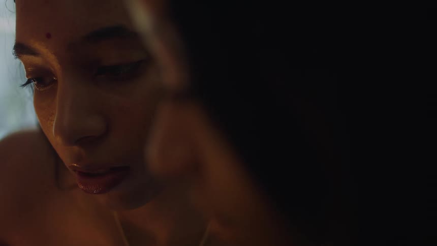 Close up of the face of two women talking inside a room lighted by candle light