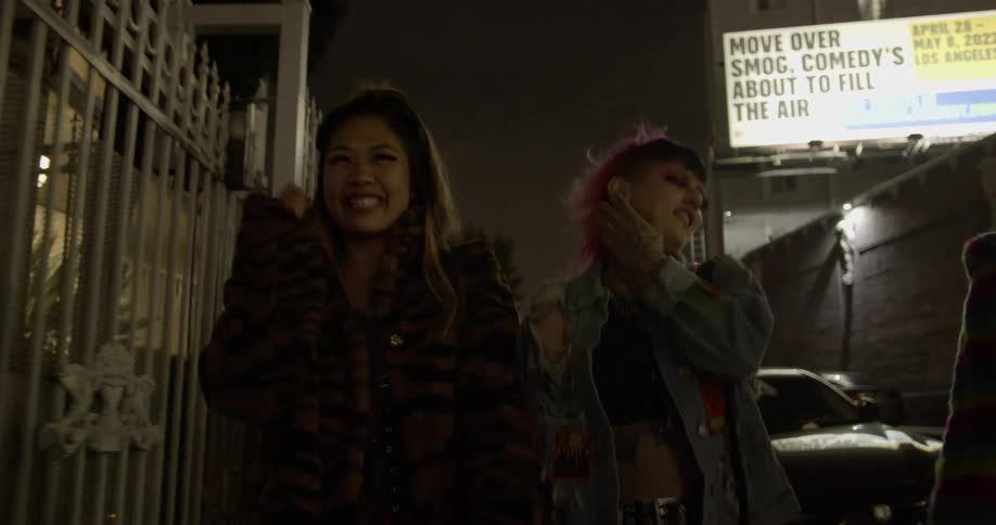 Three teenage girls are walking down a street having fun singing and hanging out together