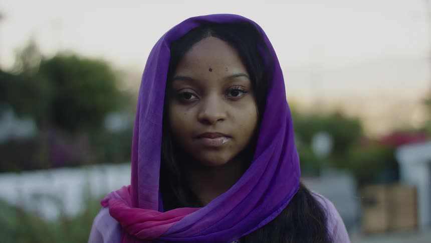A young hindu girl with a bindi on her forehead and wearing a purple scarf on her head