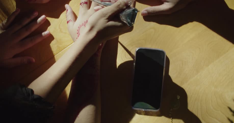 A woman applies henna tattoos on peoples hands