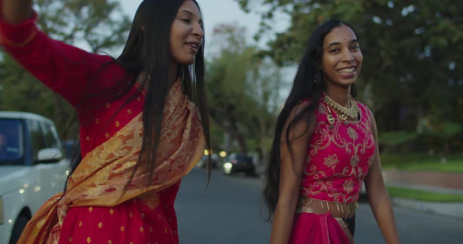 Richly dressed women stand in street in neighborhood talking and smiling