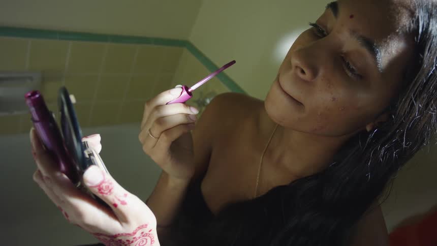 A girl is in the bathroom and putting on makeup