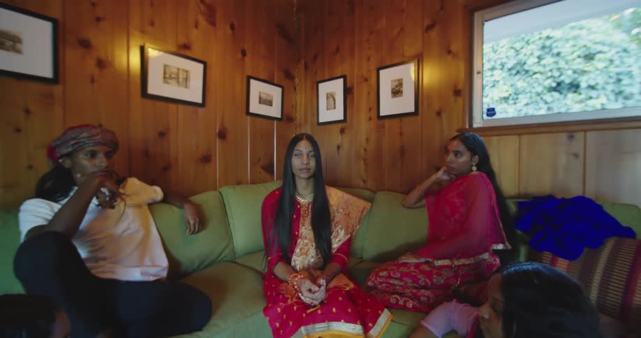 Friends and family pose in living room wearing sari