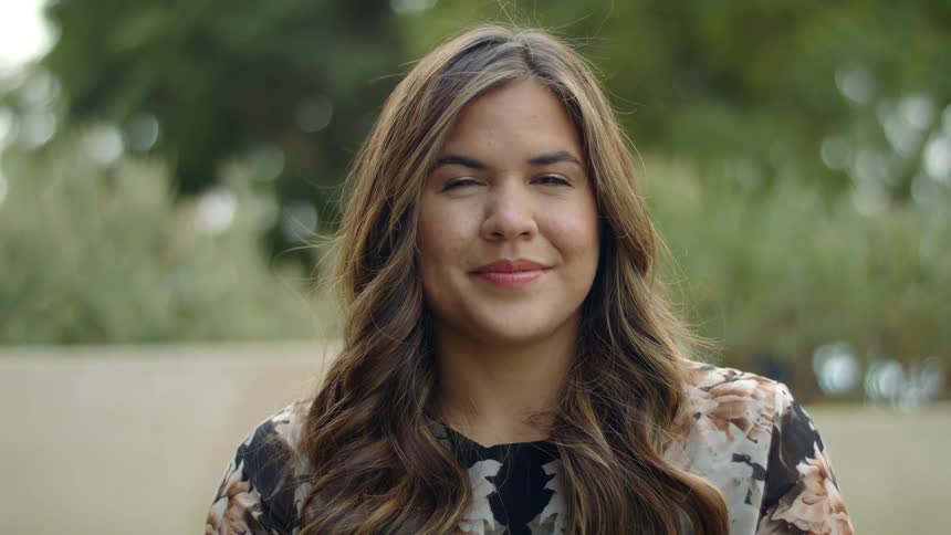 Woman stands outdoors smiling as she poses