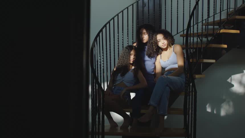 Three sisters pose for a photo on a staircase