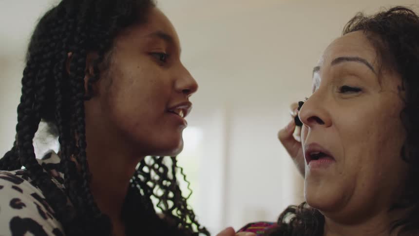 Two women are talking as they apply makeup
