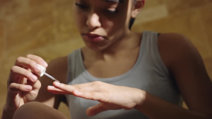 Two girls are sitting together and painting their nails