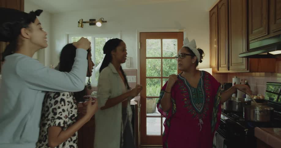 A group of people are in a kitchen and talking to one another