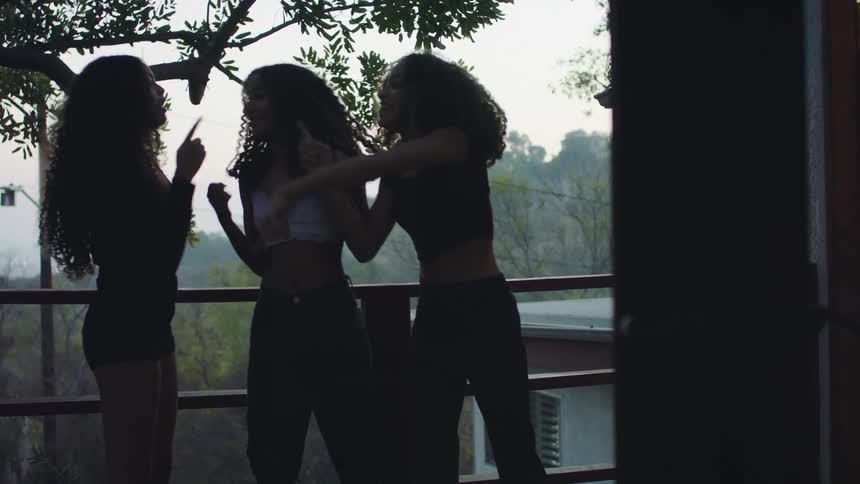 Group of young girls talking and jumping excitedly on the balcony of a house at morning