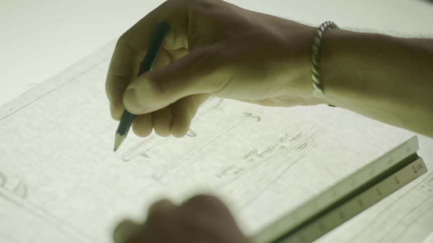 A man uses a ruler to trace lines on a diagram