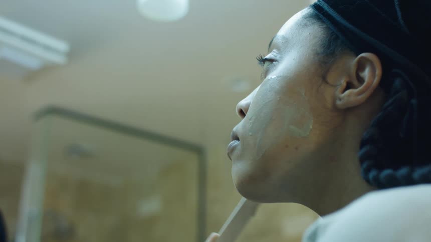 A woman applying a facial cream with a stick indoors
