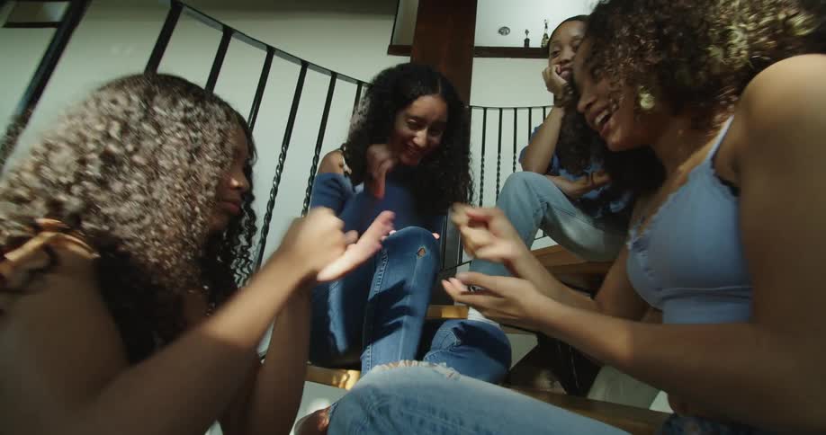 Women sit on curving staircase playing rock paper scissors