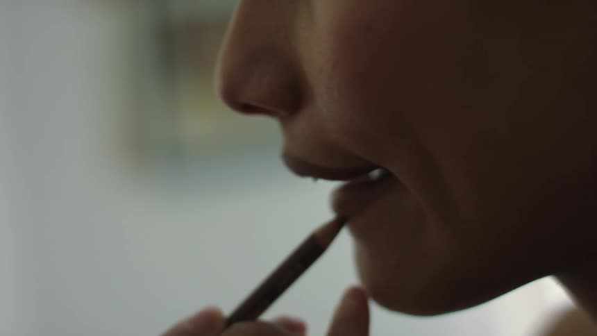 A woman is applying liner to her lips