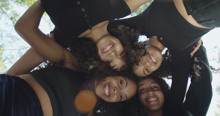 Group of teenage girls huddled around smiling to the camera standing outdoors