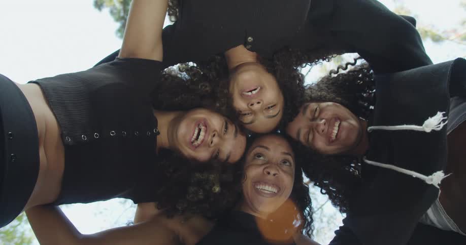 A group of friends are hugging outdoors during the daytime