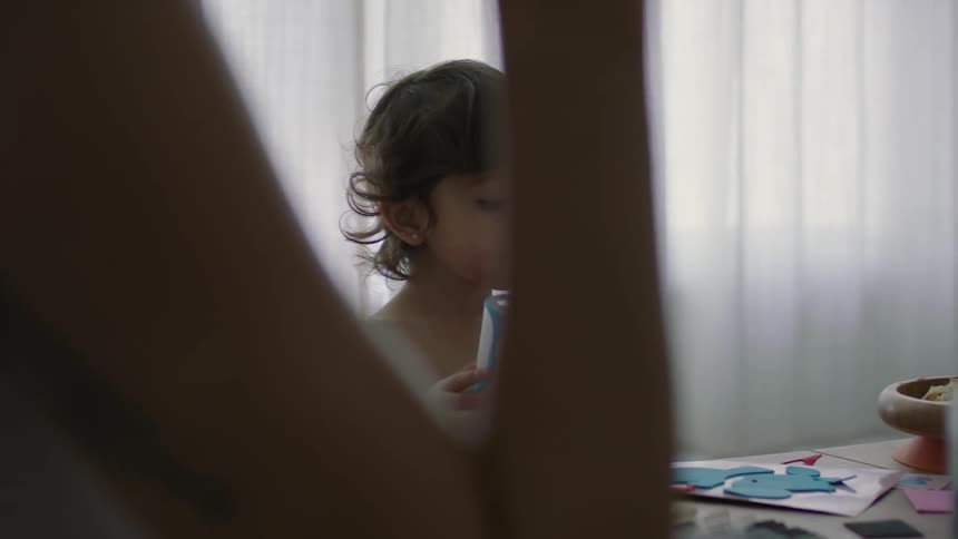 A woman sits at a table while her infant son plays with shapes