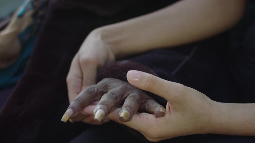 A young woman massages an older womans hands