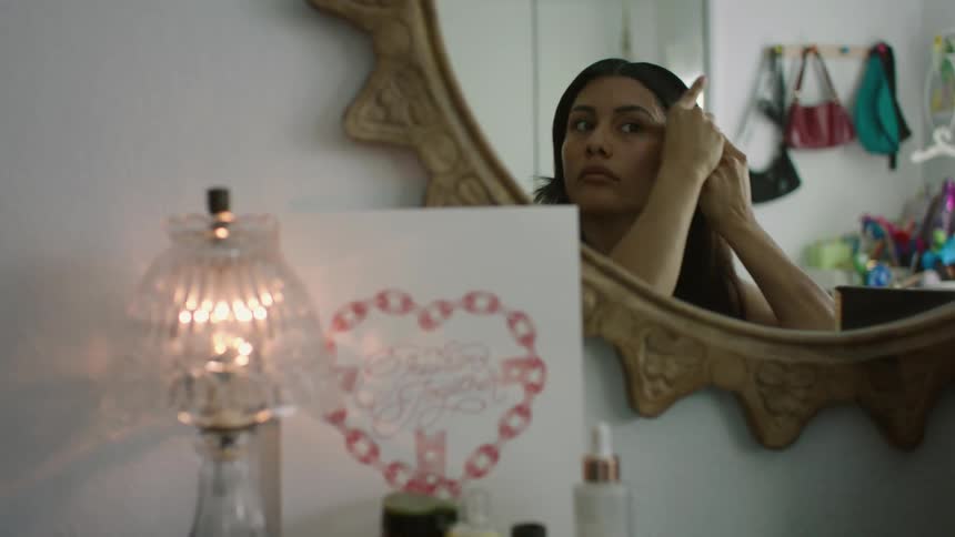 A woman is in a room looking in a mirror as she brushes her hair