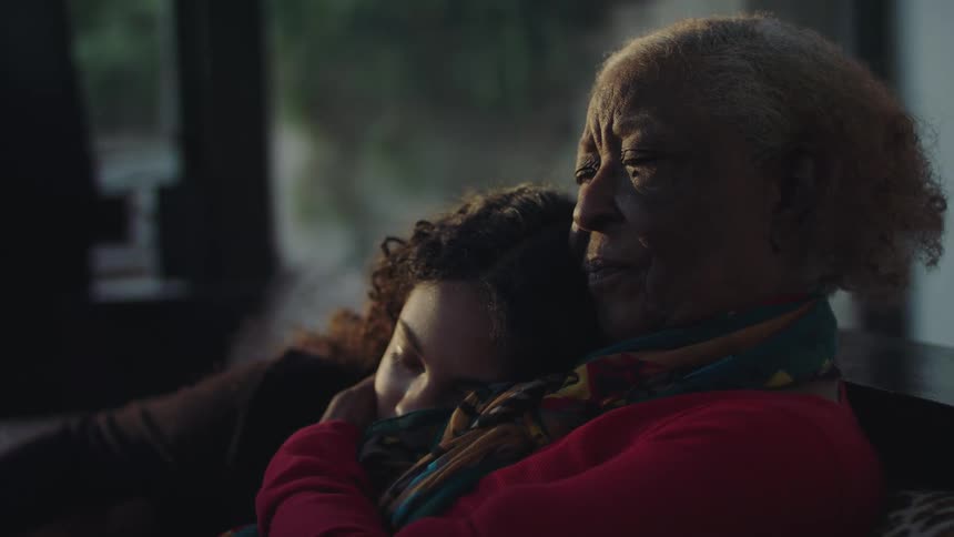 Grandmother and granddaughter sitting in the couch at home in the morning