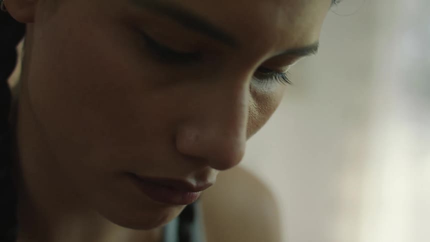 A young woman looks down as she concentrates