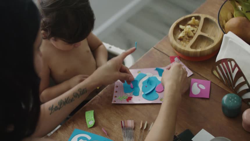 A woman helps a child with arts and crafts