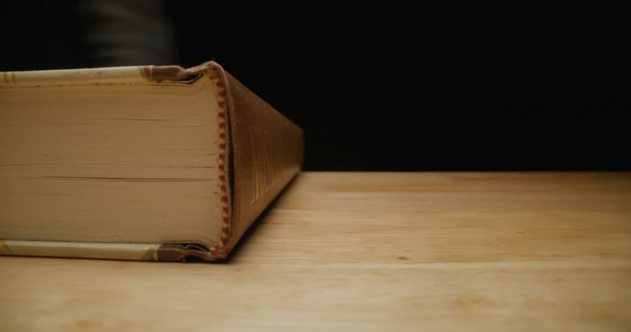 A person closing a large book on a table