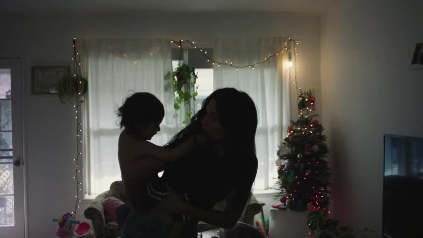 A woman is giving her son a piggy back ride in the living room