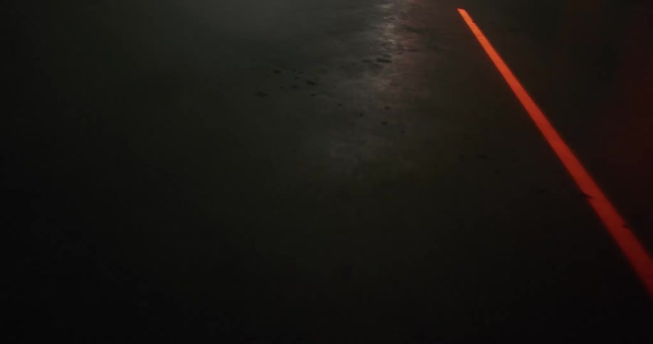 A bright orange line moves across the pavement at night