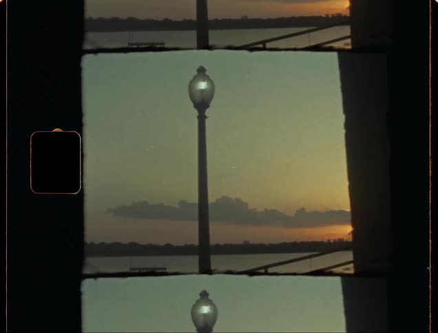 Vintage film of the sunrise across the lake behind the lamp post