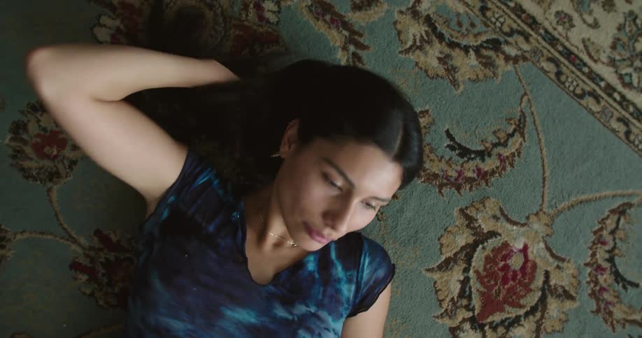 A woman is resting on a carpet indoors
