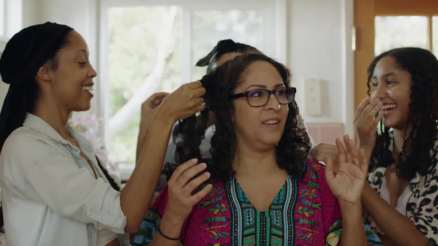 Group of young girls helping a woman with her hair at home