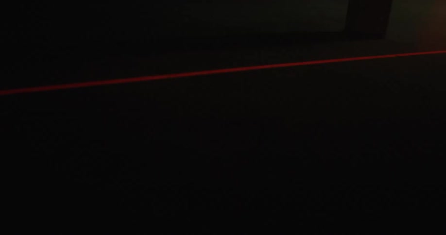 Red laser light scanning the floor inside a dimly lit room